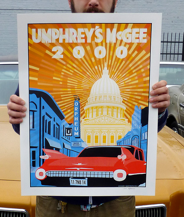 Photo of Kyle Baker holding the UM 2000 / Madison Orpheum gig poster in front of a classic car because  it was less windy at the car dealership across the street from Baker Prints